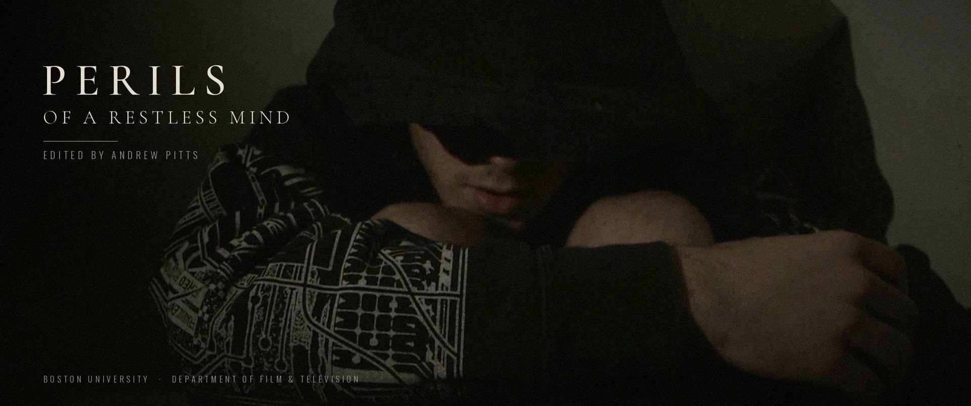 Title still from Perils of a Restless Mind: a hooded figure sits in the dark, arms folded over his knees
